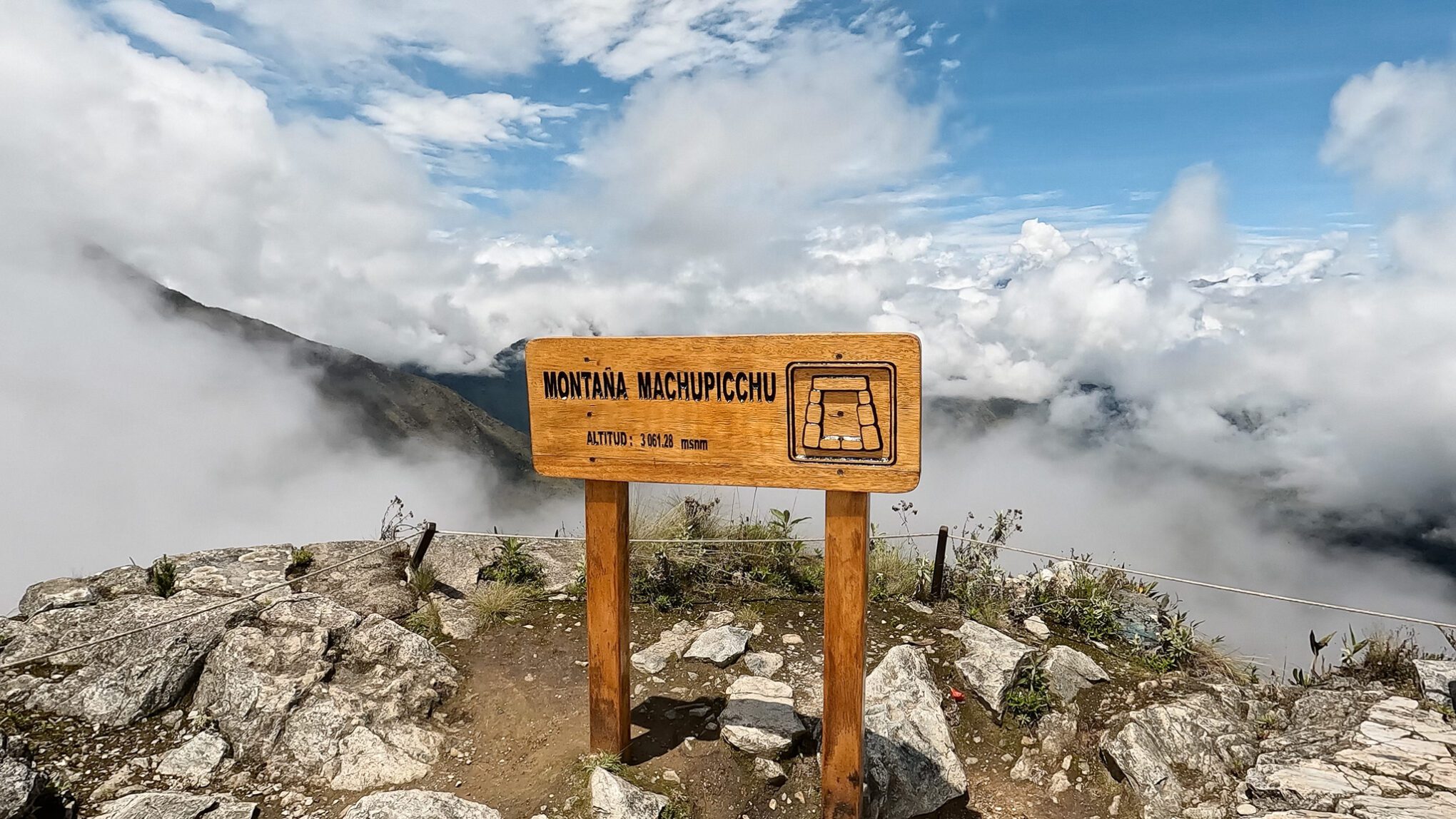 Machu Picchu Mountain sign at the top of the mountain over looking clouds 