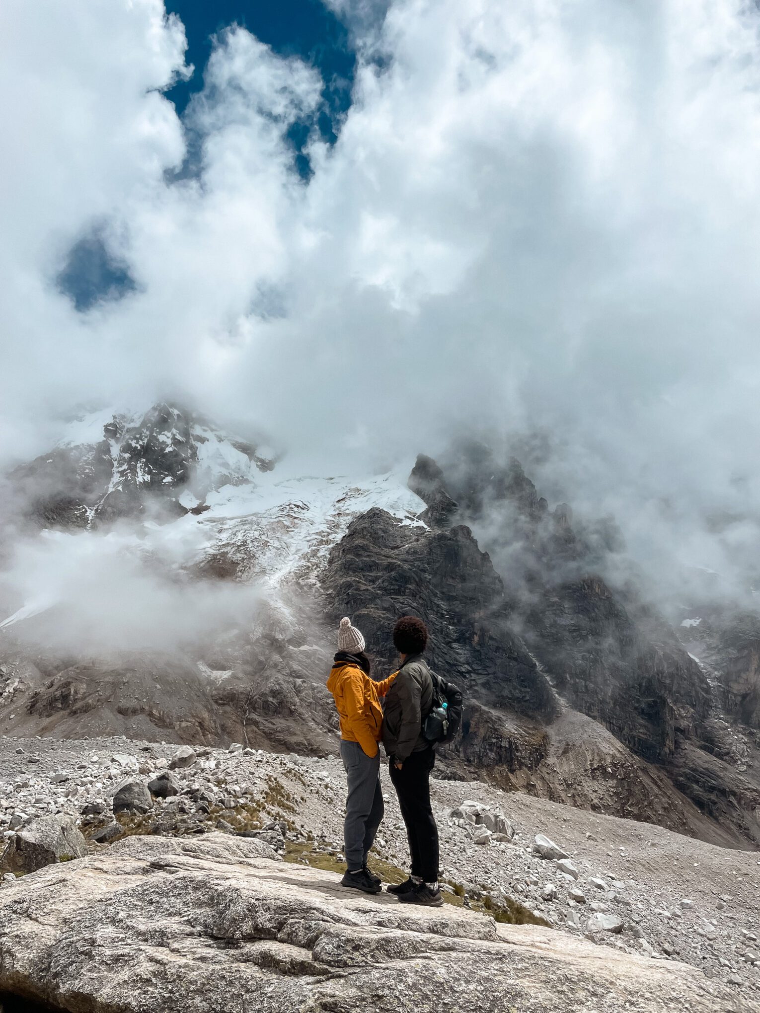 Salkantay Pass. Thais and Kelvyn standing on a rock facing Salkantay Mountain which is covered in ice