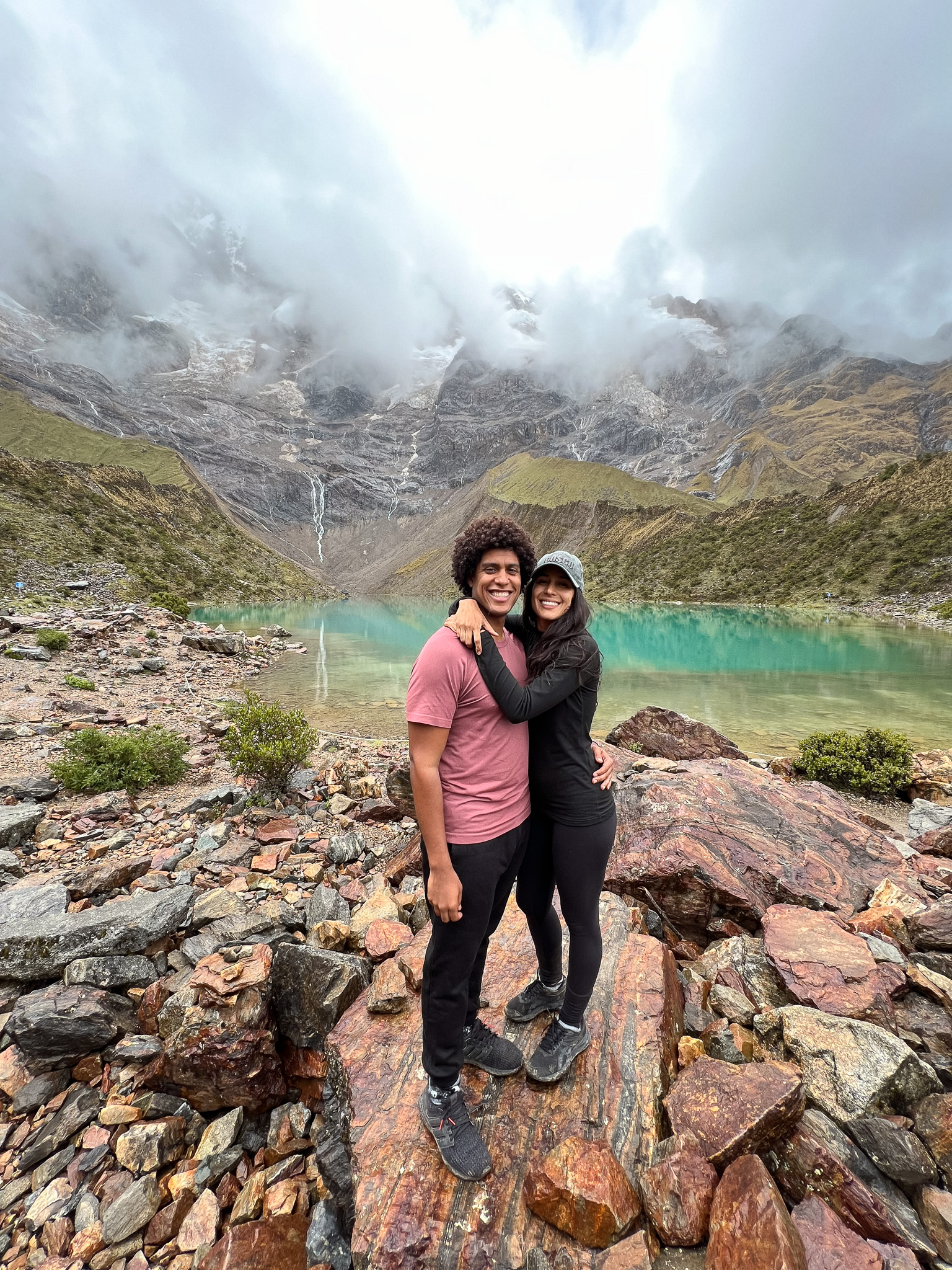 Humantay Lake. Thais and Kelvyn standing on a rock facing camera with lake in the background 