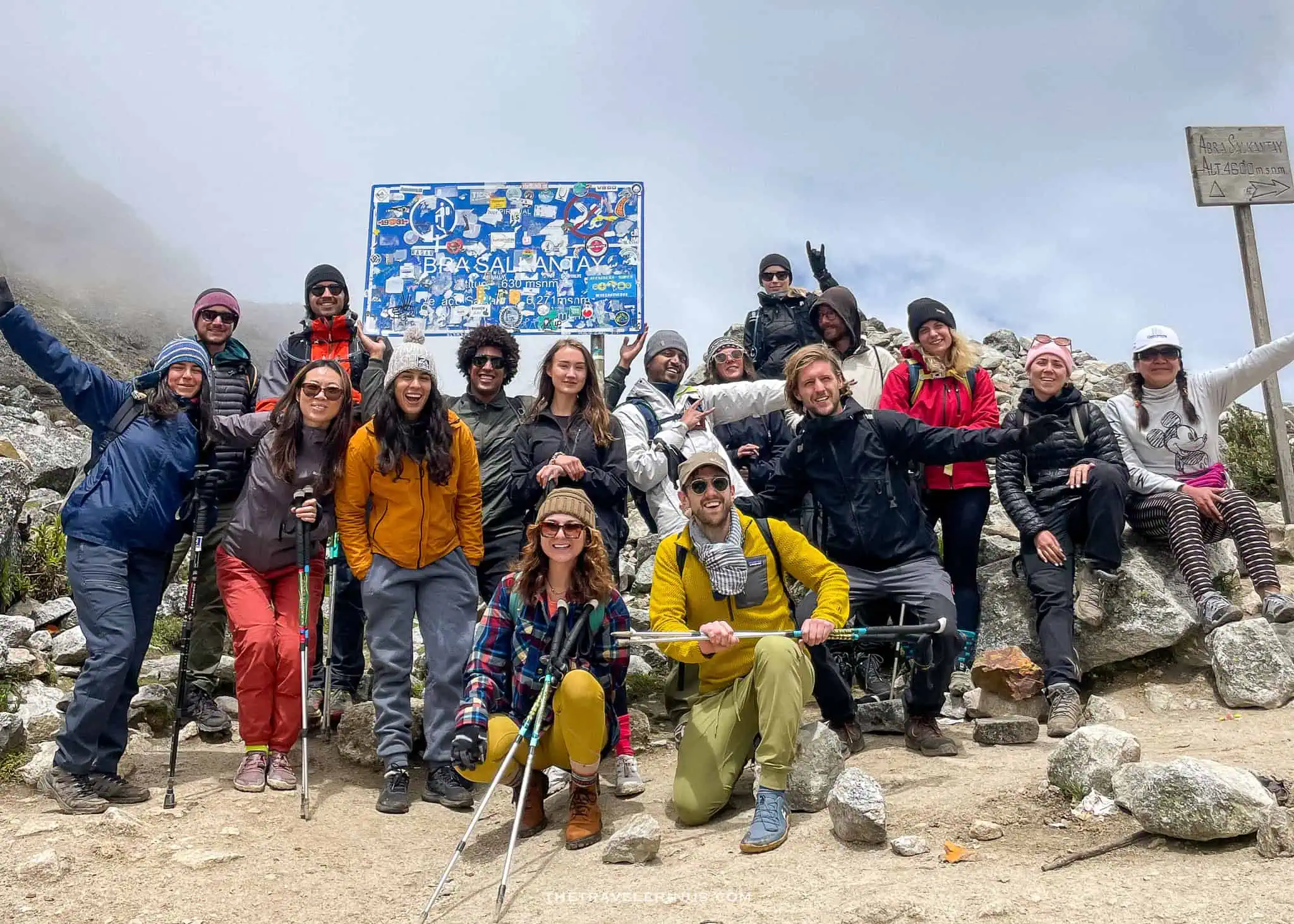 Travel in Peru. Posing in front of Salkantay sign while hiking the Salkantay trek with a group of people.